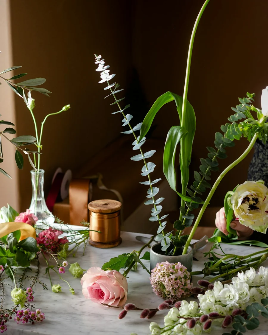 Meja kerja florist dengan bunga, vas, dan peralatan