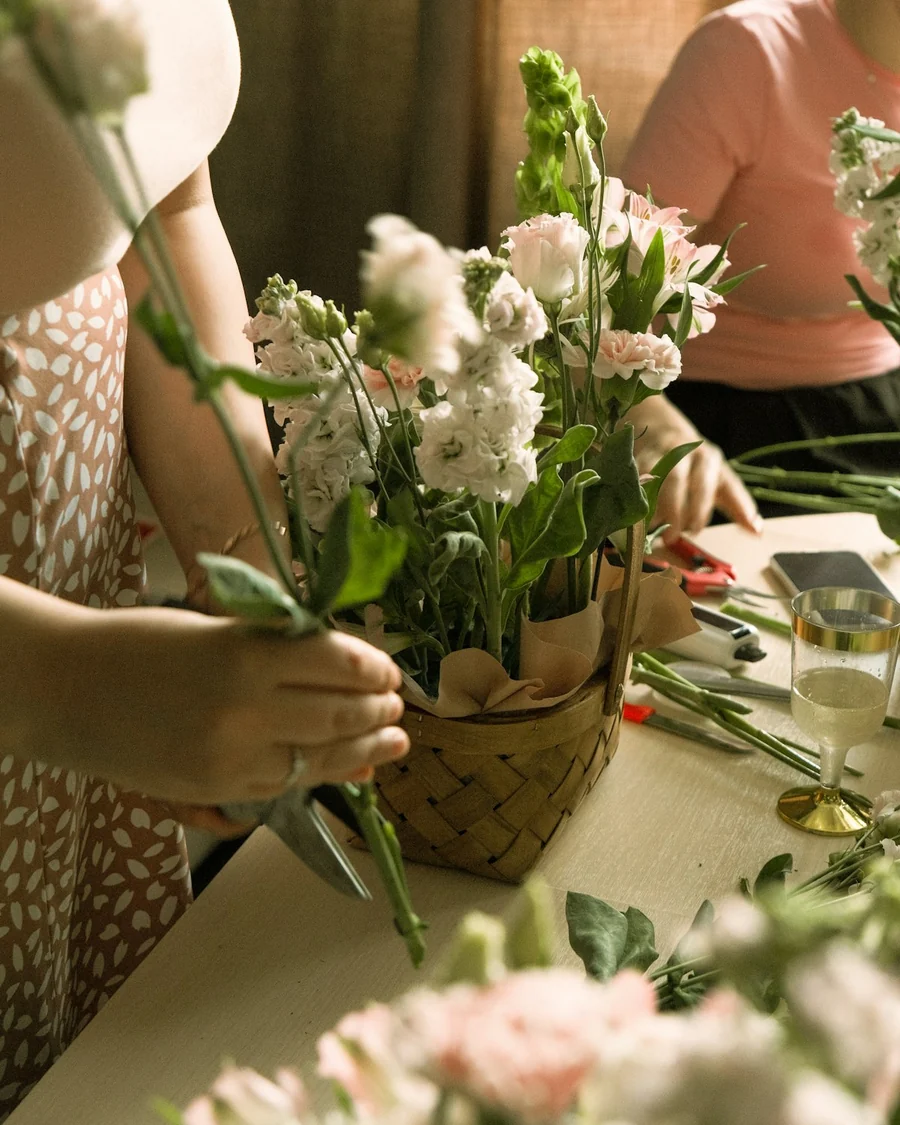 Florist menata rangkaian bunga dalam keranjang di bawah cahaya pagi