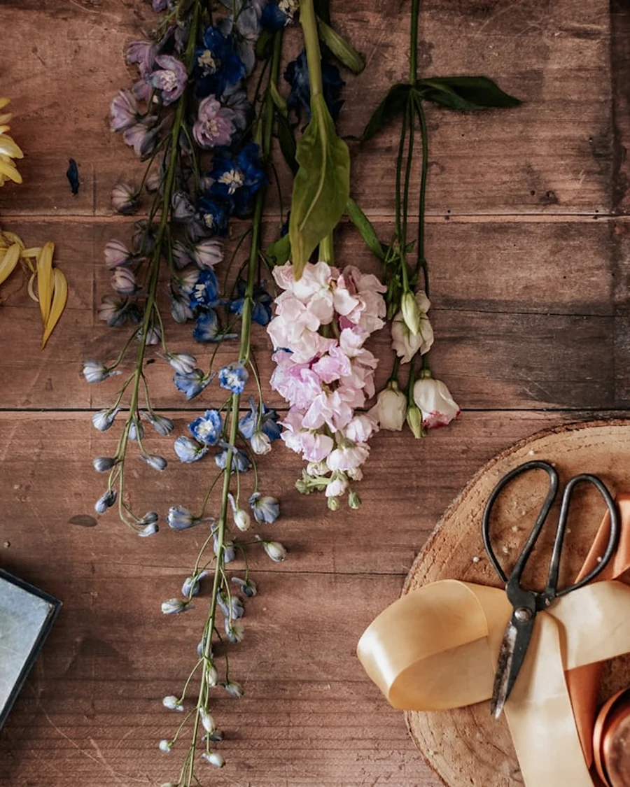 Gunting florist dan pita satin di meja kayu